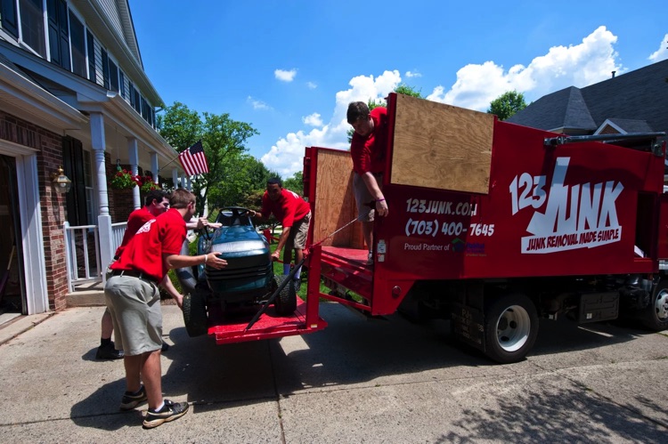 several men loading lawn mower into moving truck