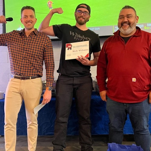 123 Junk team with one holding a certificate and flexing his arm during an award presentation