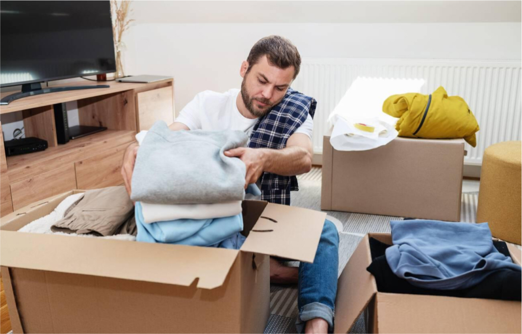 A man organizing and decluttering a room, sorting items into boxes for donation, recycling, and storage